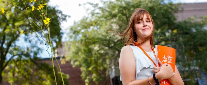 Student holding notebook outside